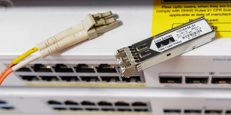 Moduł SFP (z prawej); pod nim gniazdo SFP w switchu; z lewej kompatybilny wtyk światłowodowy (LC Duplex)